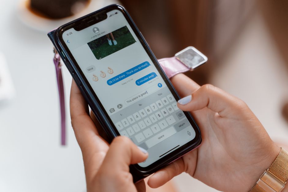 Person using a smartphone with both hands while gently supporting a sore thumb and wrist.